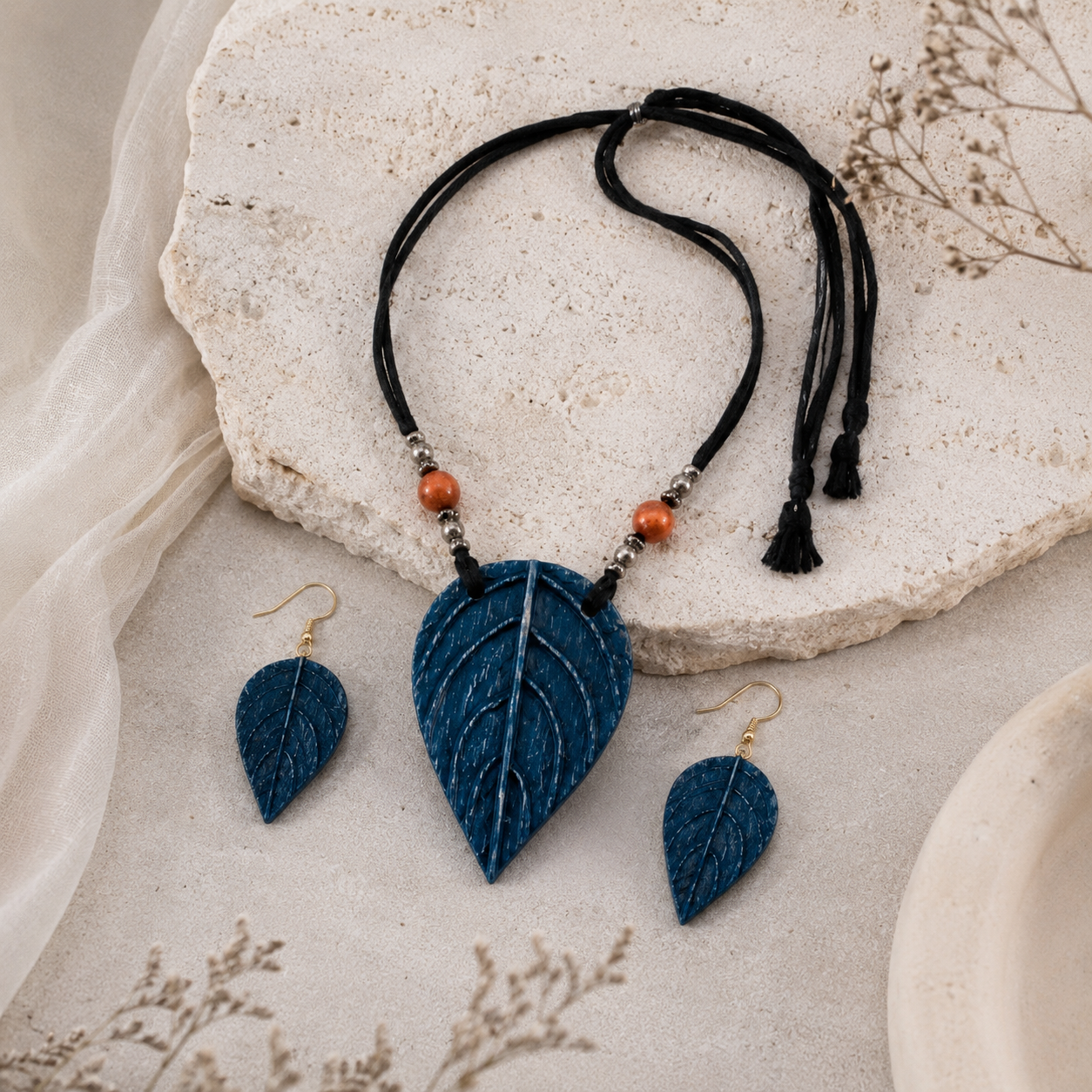 Jewelry set with blue leaf-shaped pendants on a stone surface